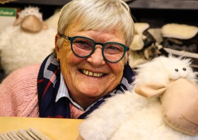 Lächelnde Standlerin mit Plüschschaf in der Woll- und Fellhütte von Alexandra Wirnsberger am Weihnachtsmarkt Mirabellplatz