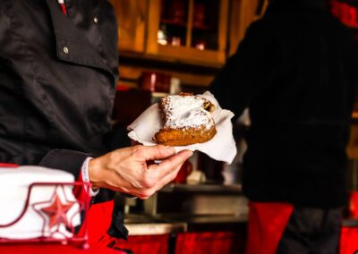 Frisch gebackener Bauernkrapfen mit Staubzucker wird an der Hütte der Christl-Alm über die Theke gereicht