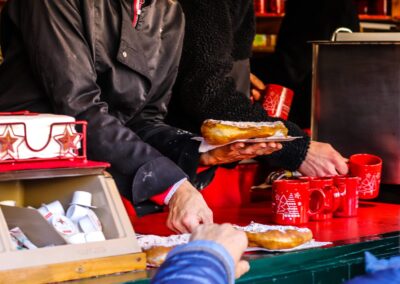 Bauernkrapfen auf Papier und rote Häferl auf der Theke der Christl-Alm am Weihnachtsmarkt Mirabellplatz