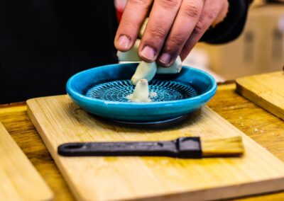 Knoblauch wird auf einer türkisen Keramikreibe zerrieben, Hütte von Gerhard Seidl