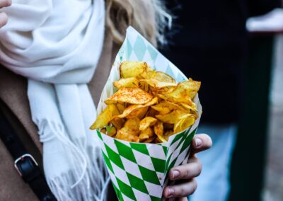 Hand hält eine Tüte mit Kartoffelchips am Weihnachtsmarkt am Mirabellplatz