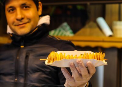 Standler zeigt eine Spiralkartoffel am Spieß an der Hütte von Markus Dimmer am Weihnachtsmarkt Mirabellplatz