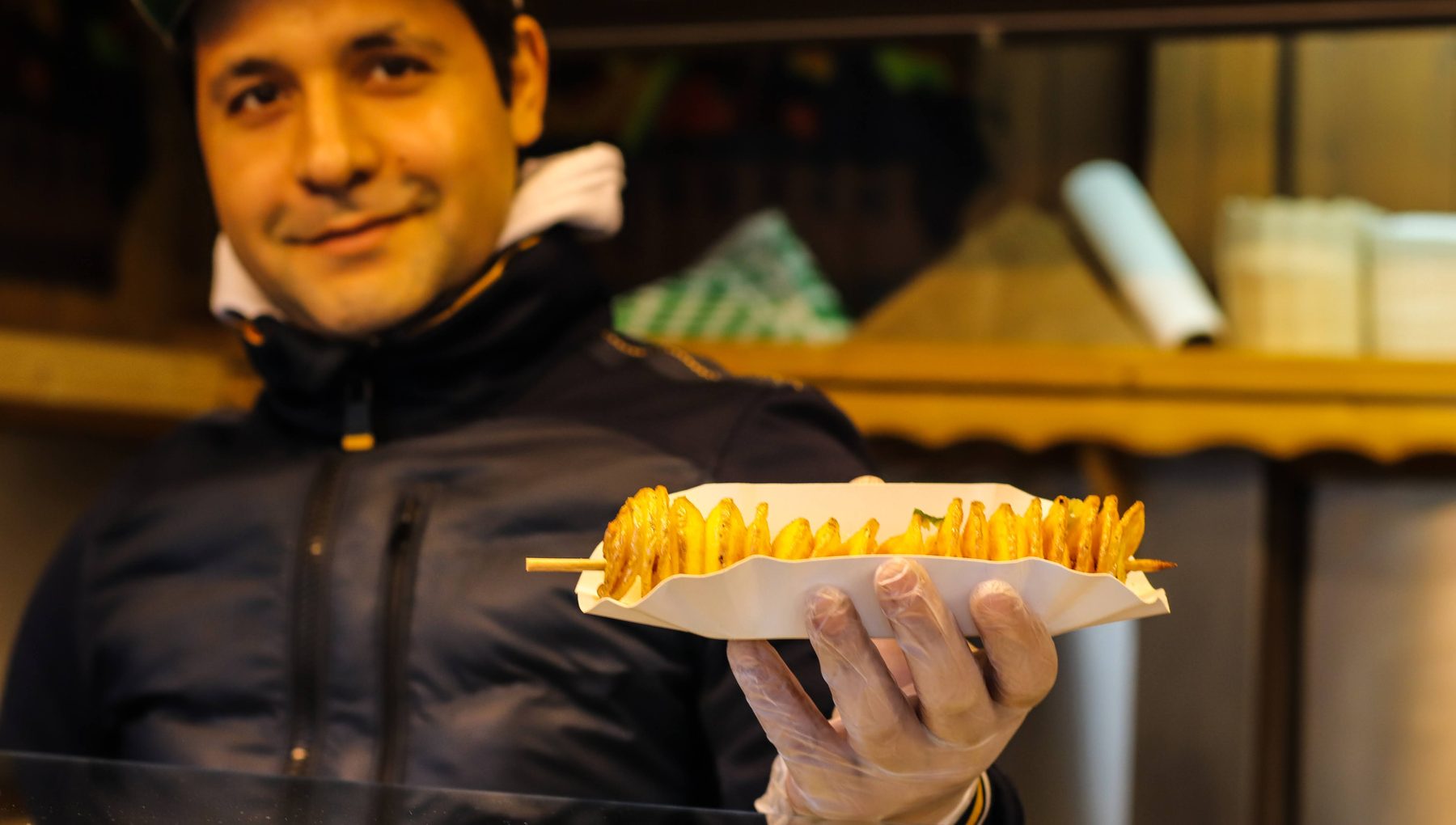 Standler zeigt eine Spiralkartoffel am Spieß an der Hütte von Markus Dimmer am Weihnachtsmarkt Mirabellplatz Standler zeigt eine Spiralkartoffel am Spieß an der Hütte von Markus Dimmer am Weihnachtsmarkt Mirabellplatz